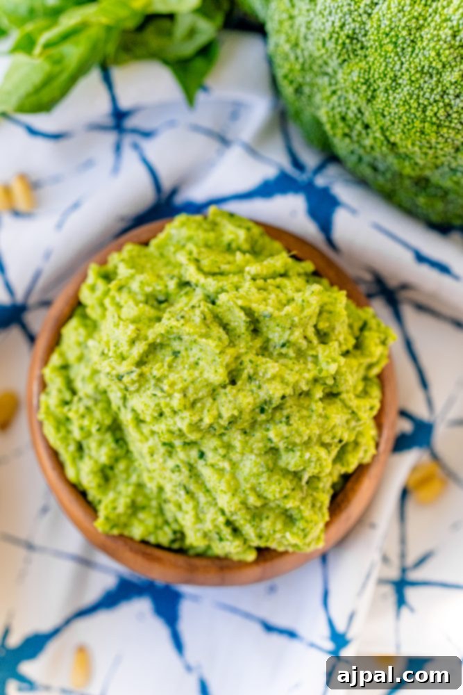 Easy and Delicious Broccoli Pesto 3 Green pesto in a wooden bowl on a blue tablecloth, ready to be served.