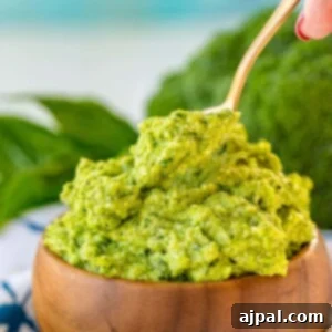 A bowl of broccoli pesto with a wooden spoon, showcasing a delicious recipe for broccoli pesto.