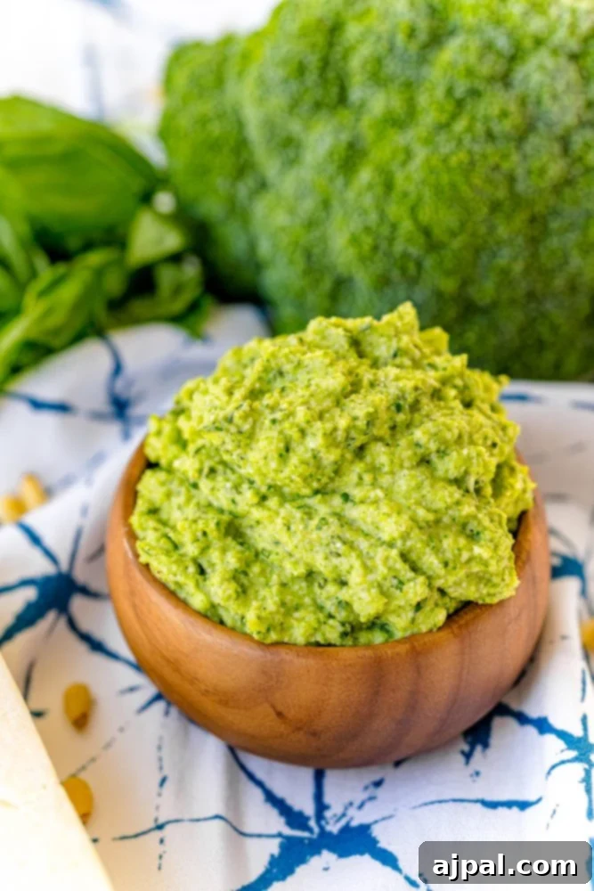 A wooden bowl filled with green pesto, featuring a delicious and easy broccoli pesto recipe that includes chickpeas.