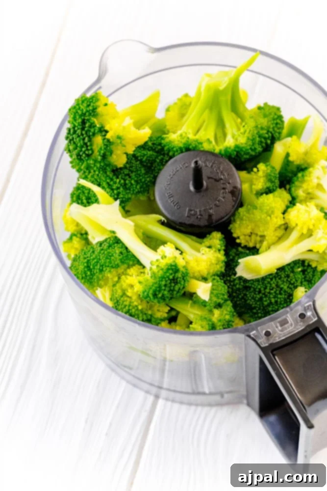 A food processor filled with fresh broccoli florets, ready to be transformed into a delicious and easy broccoli pesto.