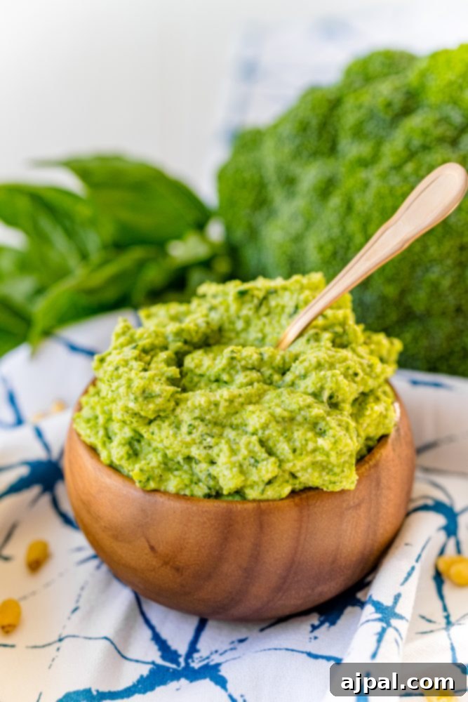 Easy and Delicious Broccoli Pesto 9 Green pesto in a wooden bowl with a spoon, showcasing a delicious easy broccoli pesto recipe.
