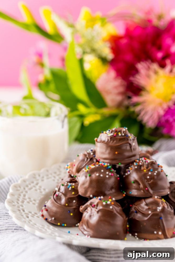 An inviting image of chocolate-dipped buttercream candies with sprinkles on a white plate, accompanied by a glass of milk, perfect for a sweet indulgence.