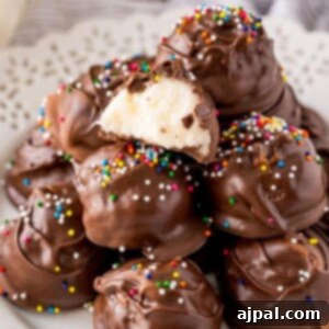 Chocolate dipped buttercream candies on a white plate with rainbow sprinkles on top, ready to serve.