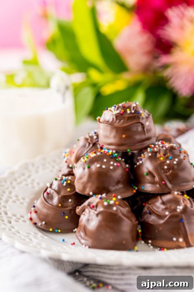 A close-up view of chocolate-covered buttercream candies with vibrant sprinkles on a white plate, highlighting their perfect texture and inviting appearance.
