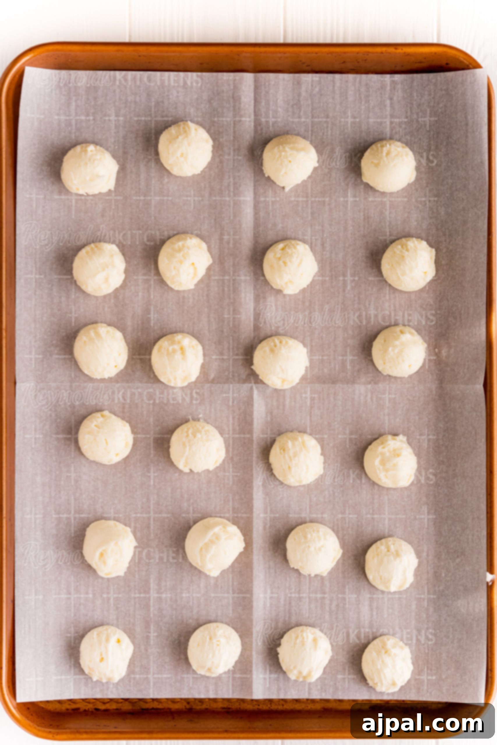 Rolled out buttercream candy balls arranged on a parchment-lined baking sheet, ready for chilling.