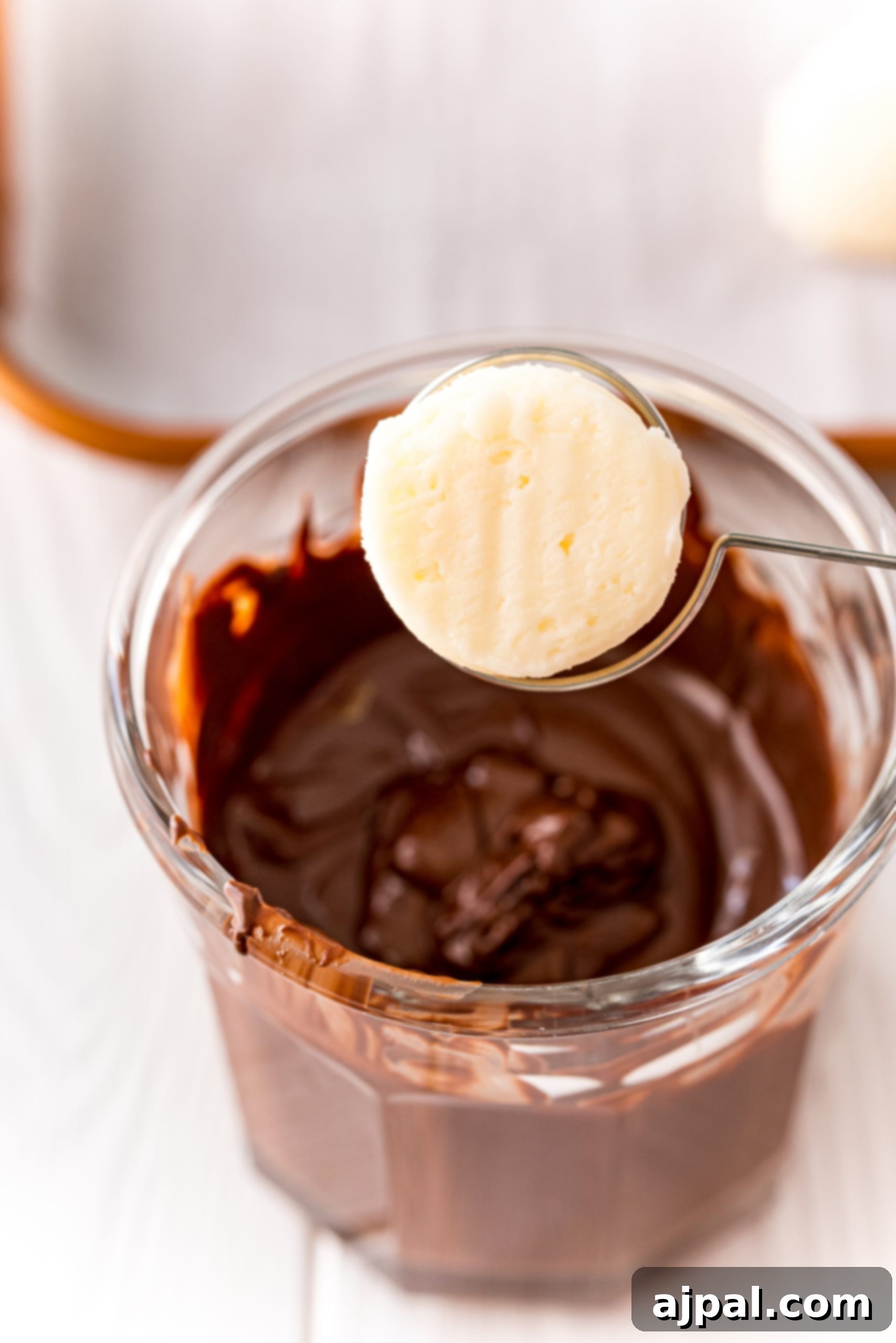 A chilled buttercream candy on a dipping spoon, poised for its chocolate coating.