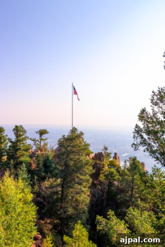 A vibrant flag fluttering proudly over a majestic rock formation, overlooking a serene lake at Cloud Camp in Colorado.