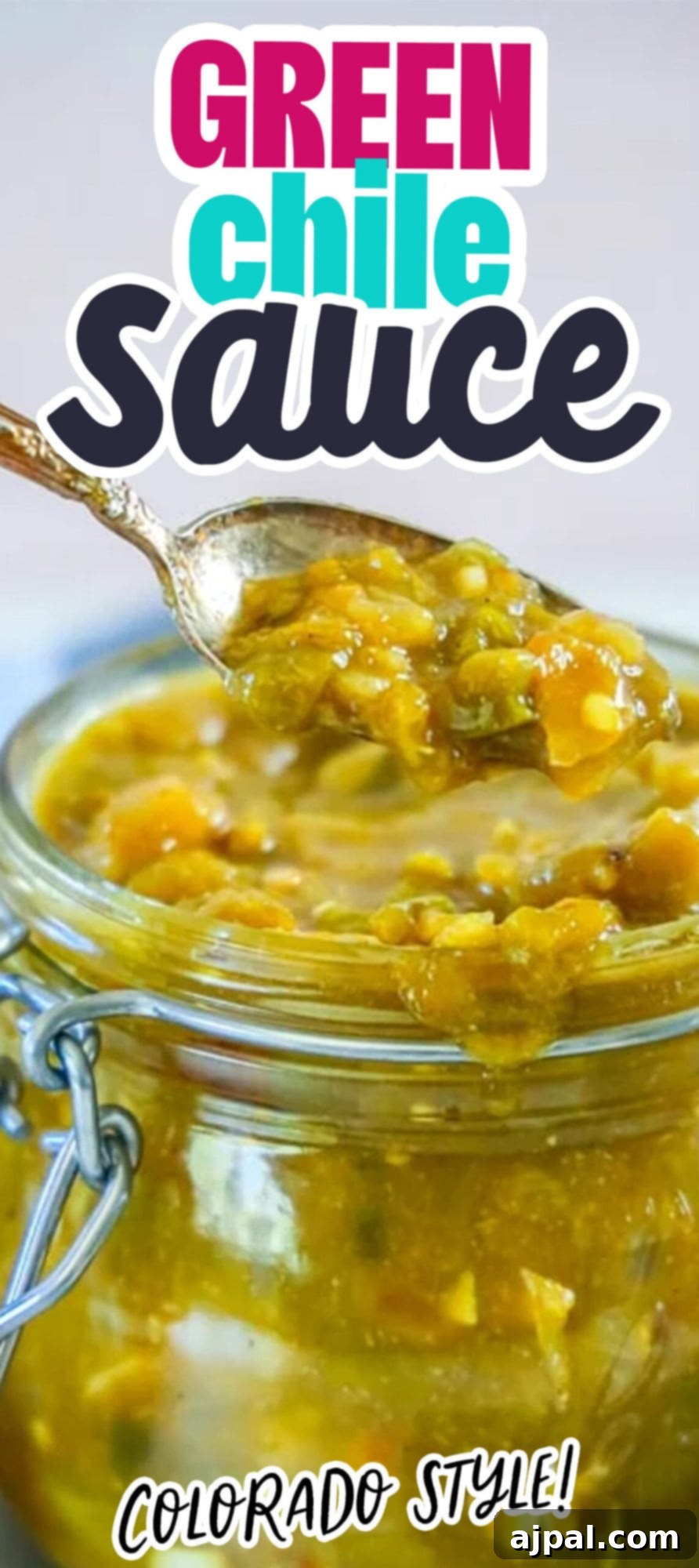 A jar of beautifully crafted green chile sauce with a spoon positioned in front, highlighting its rich texture and vibrant color, ready to elevate any dish.