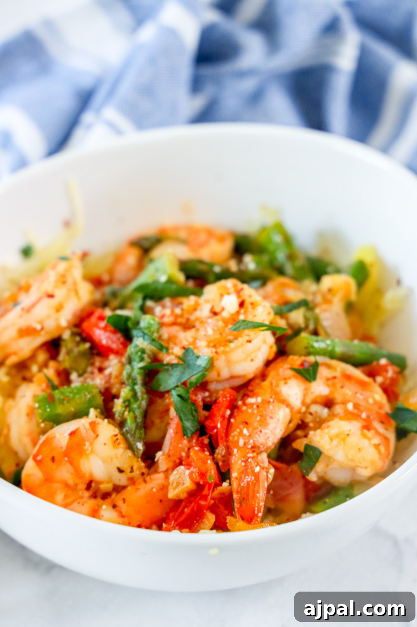 picture of shrimp and asparagus over spaghetti squash noodles in a white bowl 