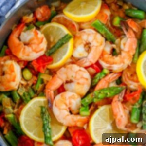 Shrimp and vegetable paella cooked in a skillet with asparagus.