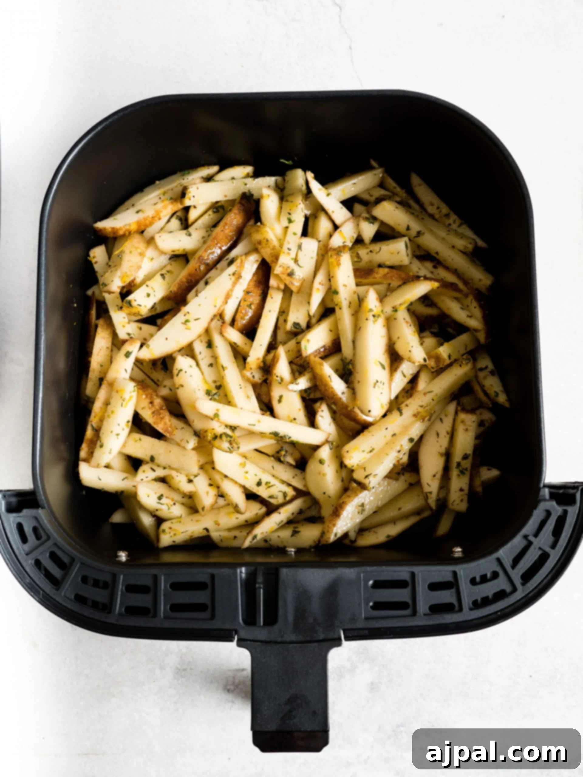 Seasoned French fries neatly arranged in an air fryer basket.