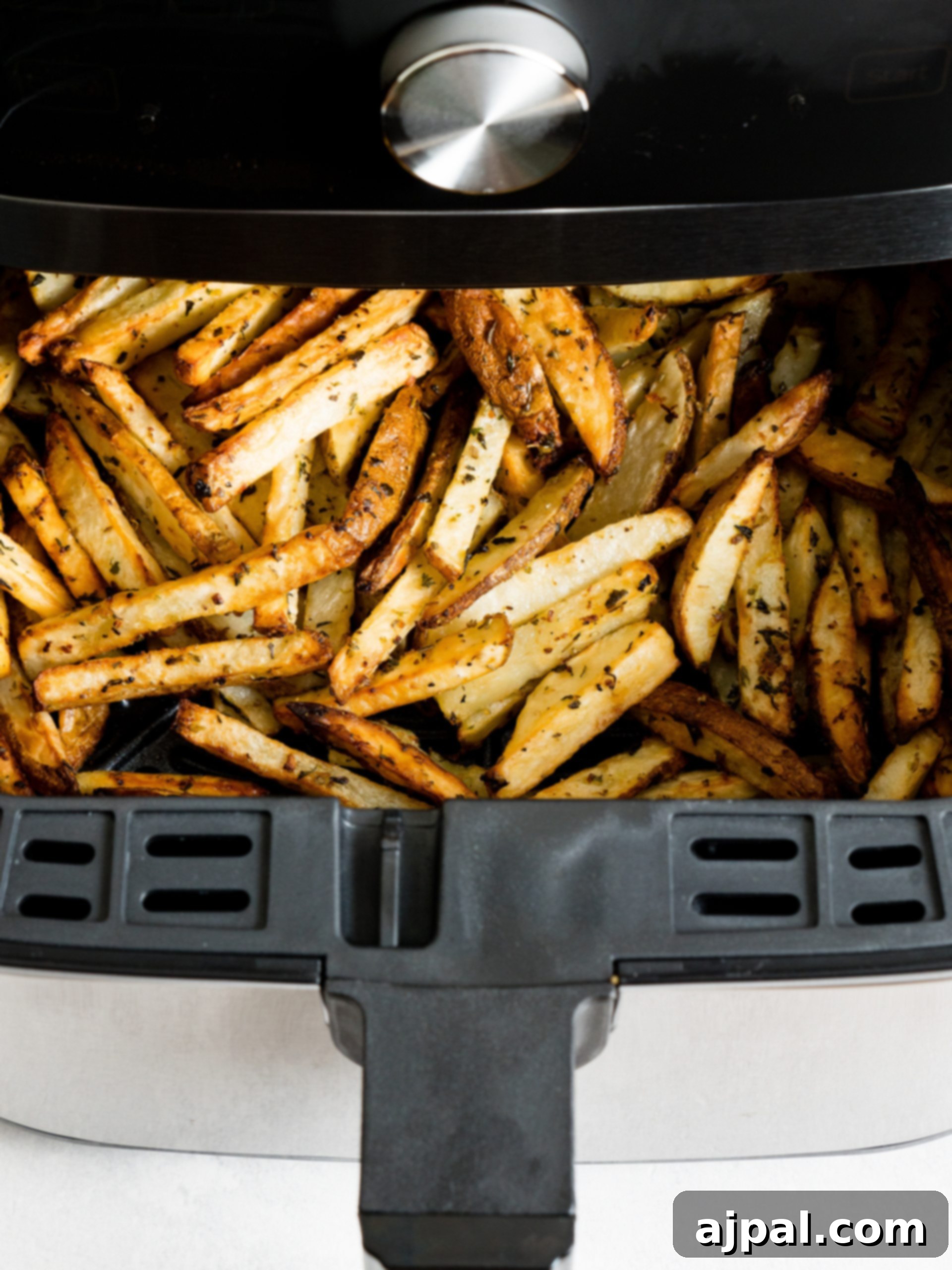Crispy, golden-brown French fries in an air fryer basket, freshly cooked.