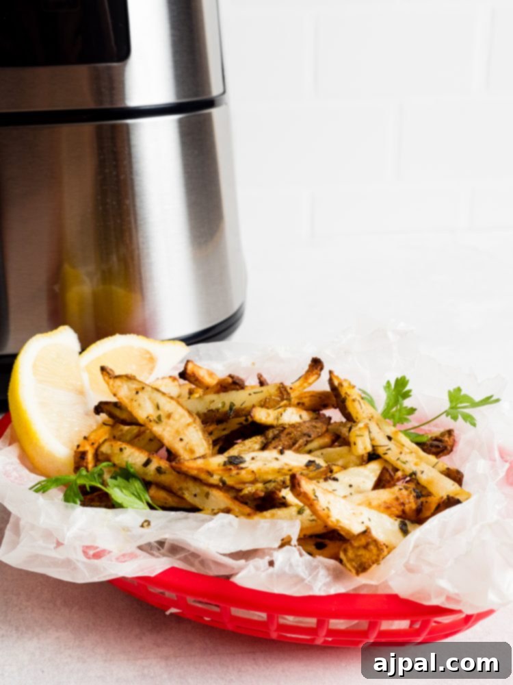 A basket of lemon garlic French fries cooling in front of an active air fryer, showing the golden-brown crispiness.