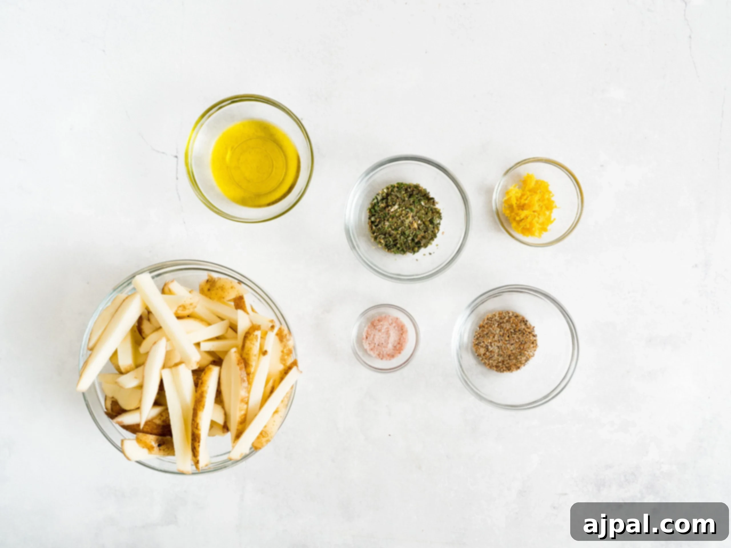 Raw potato slices, oil, and seasoning ingredients laid out for air fryer French fries.