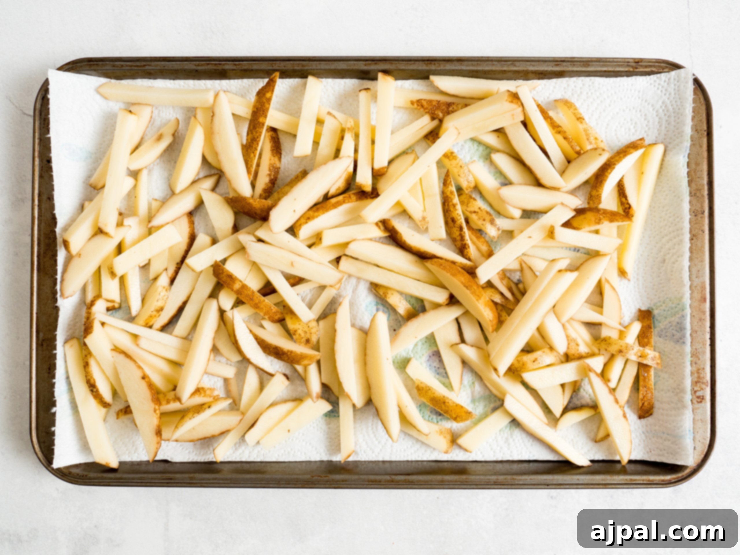 Sliced potatoes drying on paper towels, prepped for air frying.