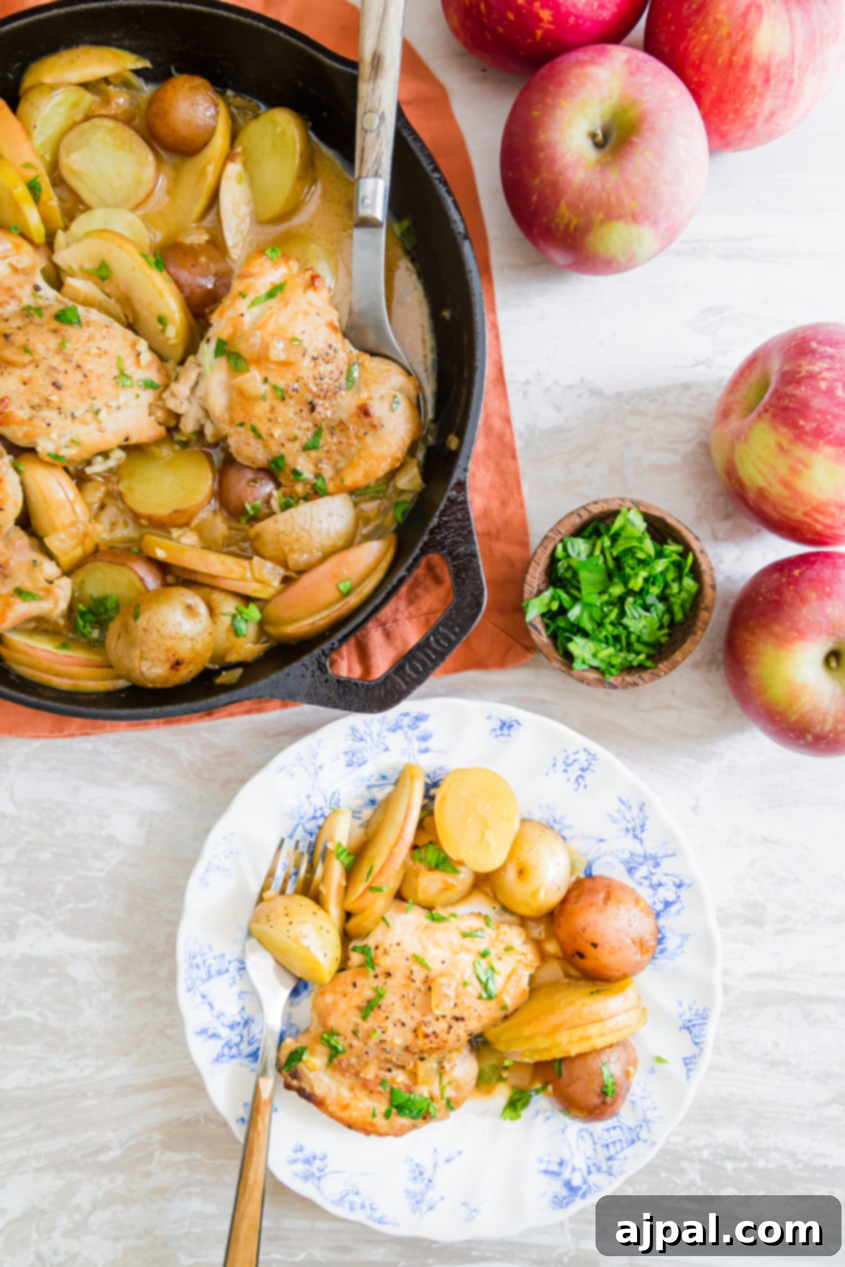 picture of chicken thigh, potatoes, apple slices in a mustard sauce on a plate