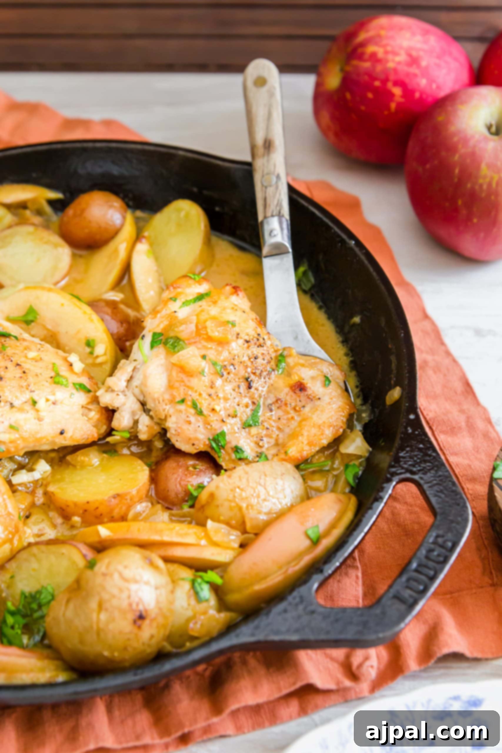 picture of chicken thigh, potatoes, apple slices in a mustard sauce in a pan