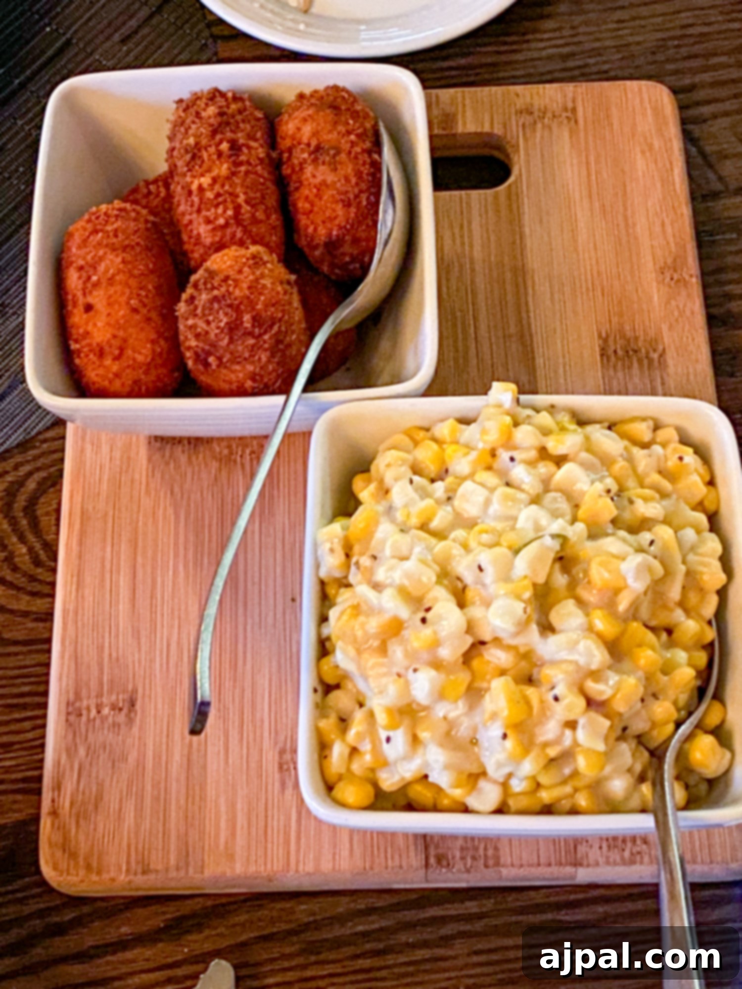An array of delicious side dishes presented on a wooden cutting board at Twenty One Steak in Pueblo.