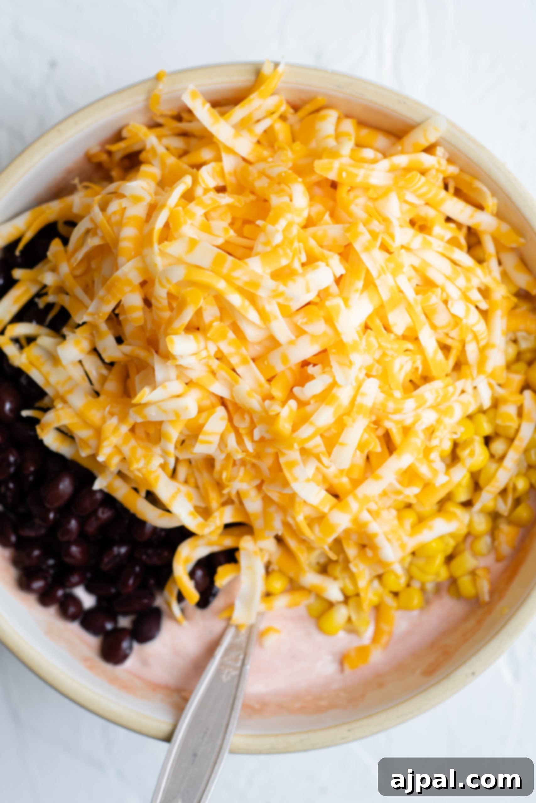 Crunchy Doritos Chicken Casserole 10 A bowl with black beans, corn, and shredded cheese topped with chicken and crushed Doritos for a flavorful casserole.