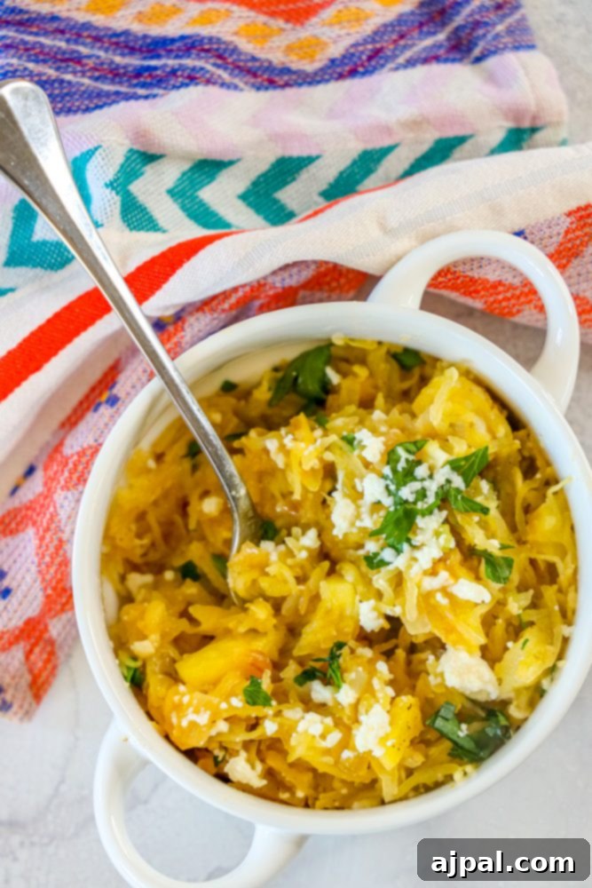 A beautifully presented bowl of spicy spaghetti squash with green chile sauce, garnished with fresh feta cheese and parsley