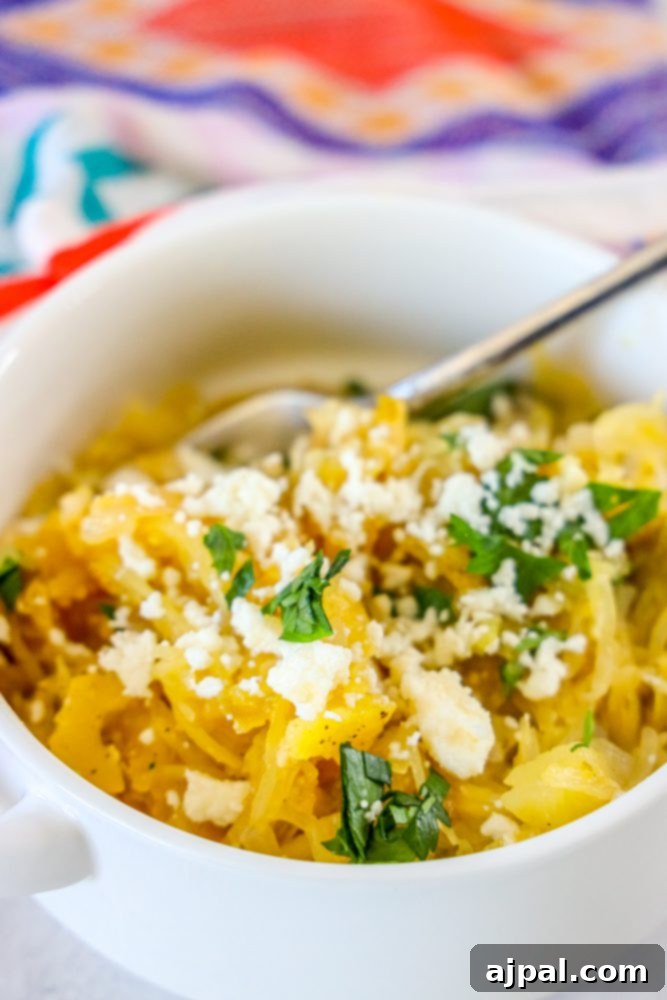 A comforting bowl of spaghetti squash soup infused with spicy green chile, garnished with feta cheese and parsley.