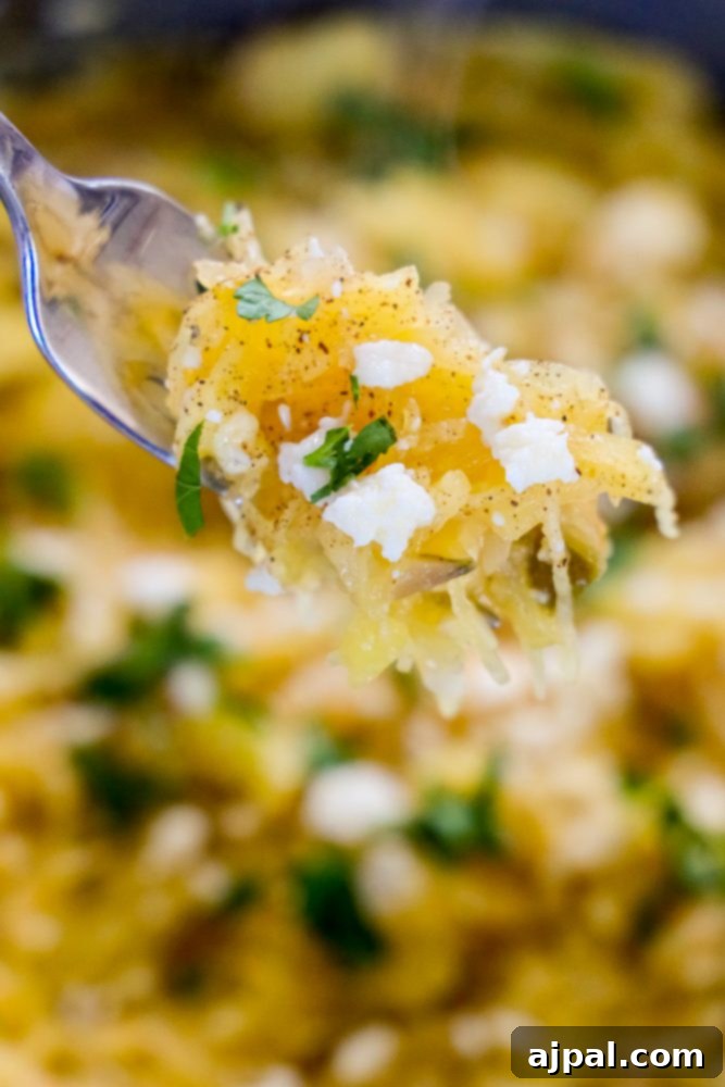 A fork lifts a generous portion of green chile spaghetti squash, showcasing the vibrant sauce and cheese.