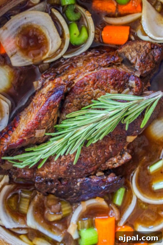 Fall-Apart Tender Pot Roast 2 A succulent pot roast with gravy, celery, onion, carrots, and fresh rosemary sprigs, presented beautifully in a Dutch oven.