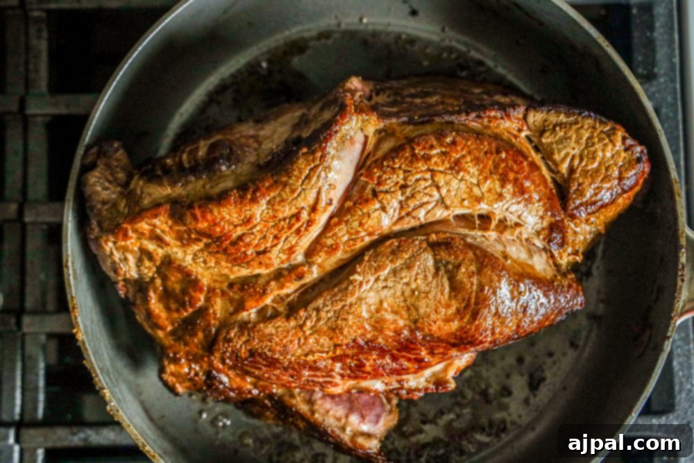Fall-Apart Tender Pot Roast 4 A large piece of chuck roast being browned in a heavy skillet with melted butter.