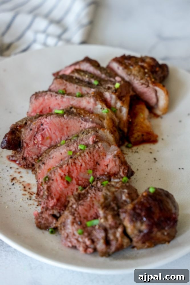 Master Your Air Fryer Steaks 10 A perfectly sliced air-fried steak on a white plate, garnished with green onions, demonstrating a flawless cook.