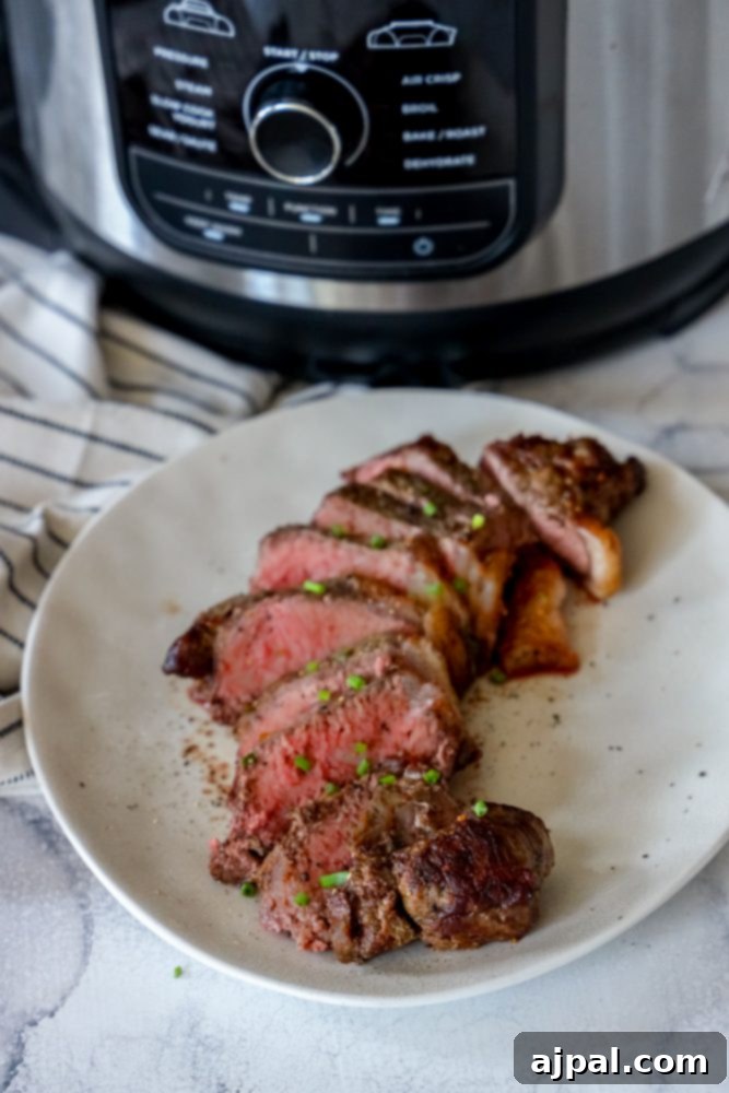 Master Your Air Fryer Steaks 3 Slices of a medium-rare New York strip steak arranged beautifully on a white plate, with an air fryer in the background.
