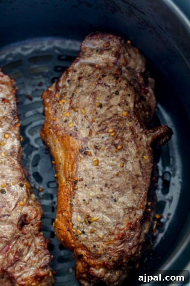 Master Your Air Fryer Steaks 8 A single juicy steak being cooked to perfection inside an air fryer, showcasing the hot air circulation.