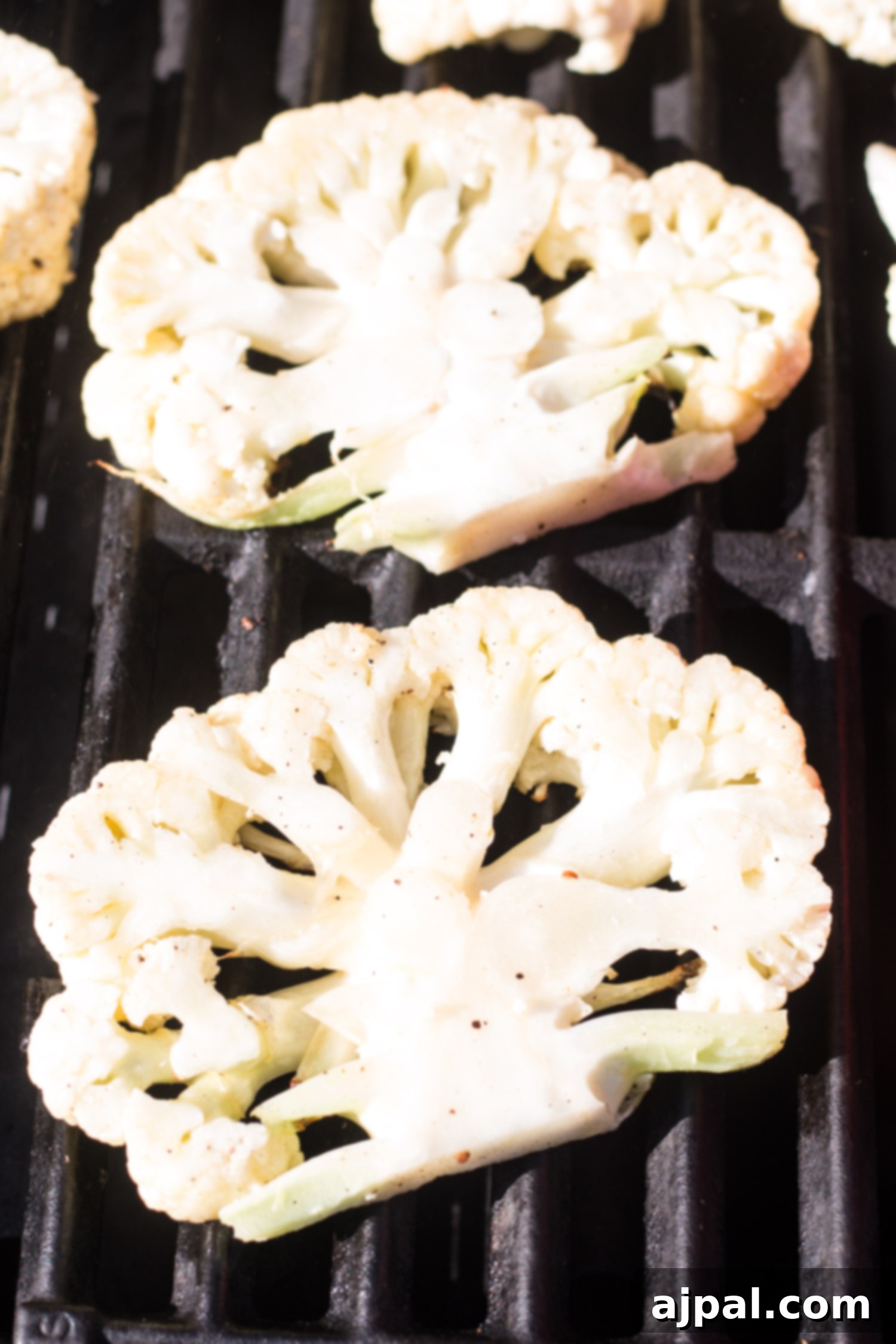 Effortless Cauliflower Steaks with Tangy Red Pepper Sauce 12 Close-up of grilled cauliflower steaks, perfectly charred and drizzled with a vibrant red pepper sauce.