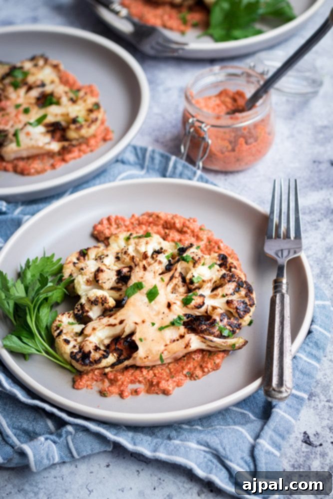 Effortless Cauliflower Steaks with Tangy Red Pepper Sauce 14 A delectable cauliflower steak, perfectly grilled and generously topped with rich red pepper sauce, served on a plate with a fork.