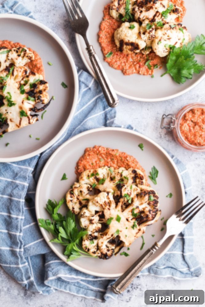 Effortless Cauliflower Steaks with Tangy Red Pepper Sauce 4 Three beautifully plated easy grilled cauliflower steaks, each generously topped with bright red pepper sauce.