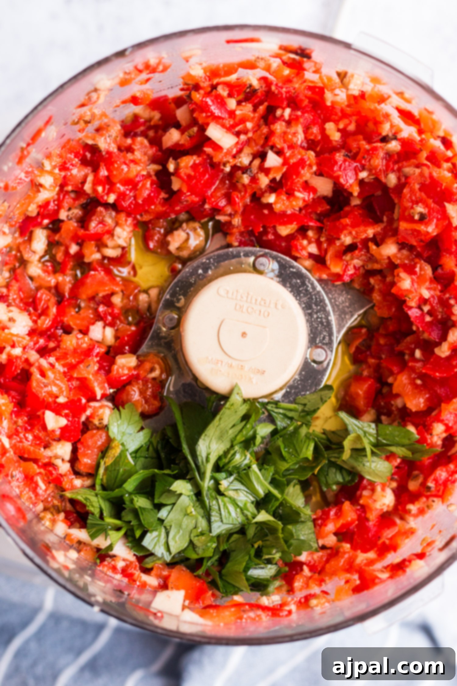Effortless Cauliflower Steaks with Tangy Red Pepper Sauce 7 A food processor filled with vibrant red peppers and herbs, ready to be blended into the delicious sauce for cauliflower steaks.