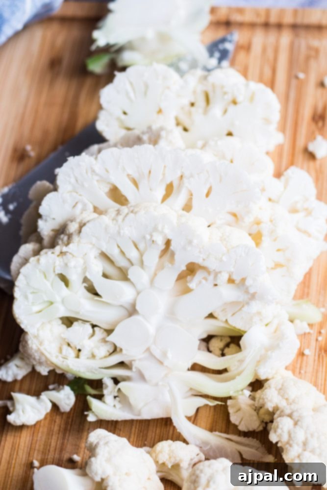 Effortless Cauliflower Steaks with Tangy Red Pepper Sauce 9 Slices of vegan cauliflower steaks neatly arranged on a cutting board, ready for grilling or roasting.