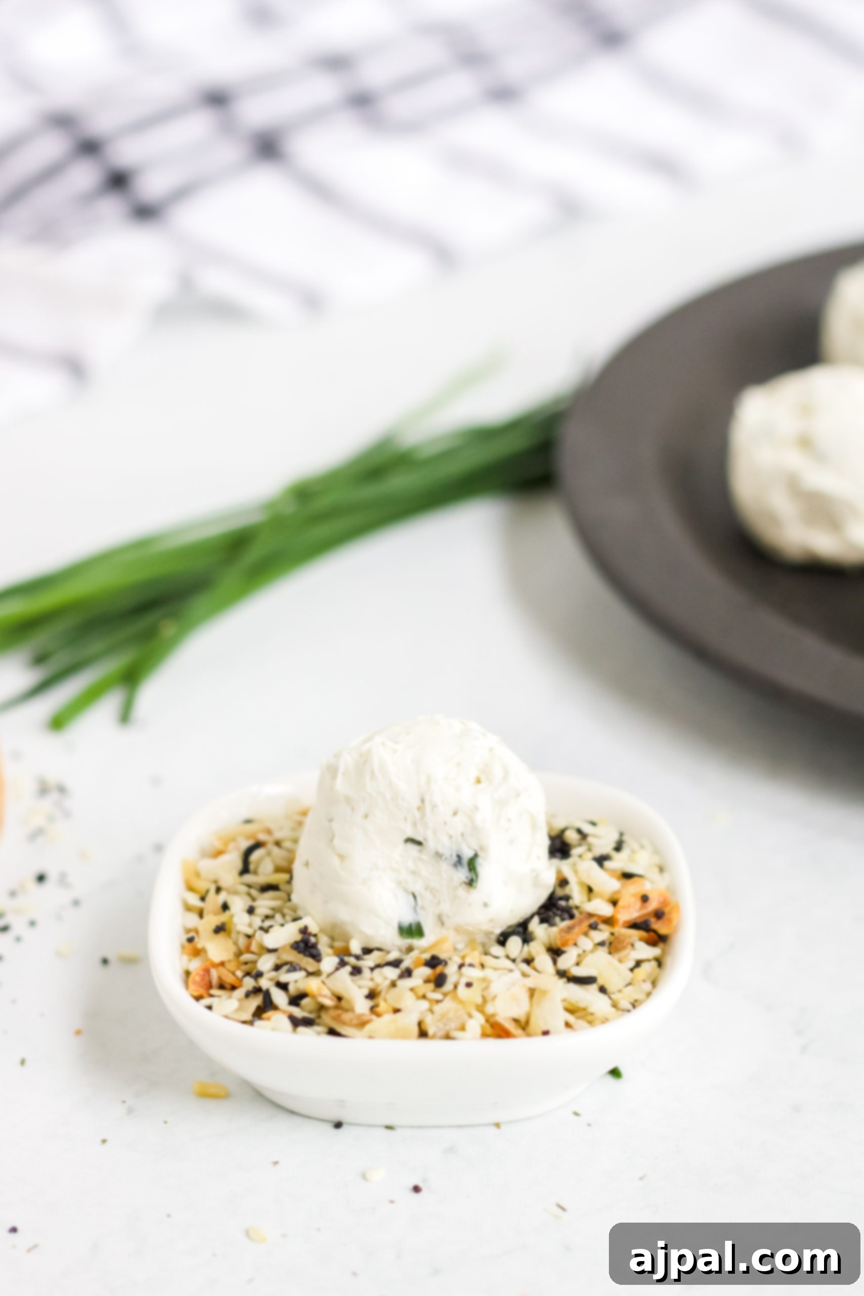 Savory Keto Everything Bagel Fat Bomb 8 A plate with a bowl of hummus and a bowl of toasted sesame seeds, featuring an Everything Bagel Keto Fat Bomb Recipe.