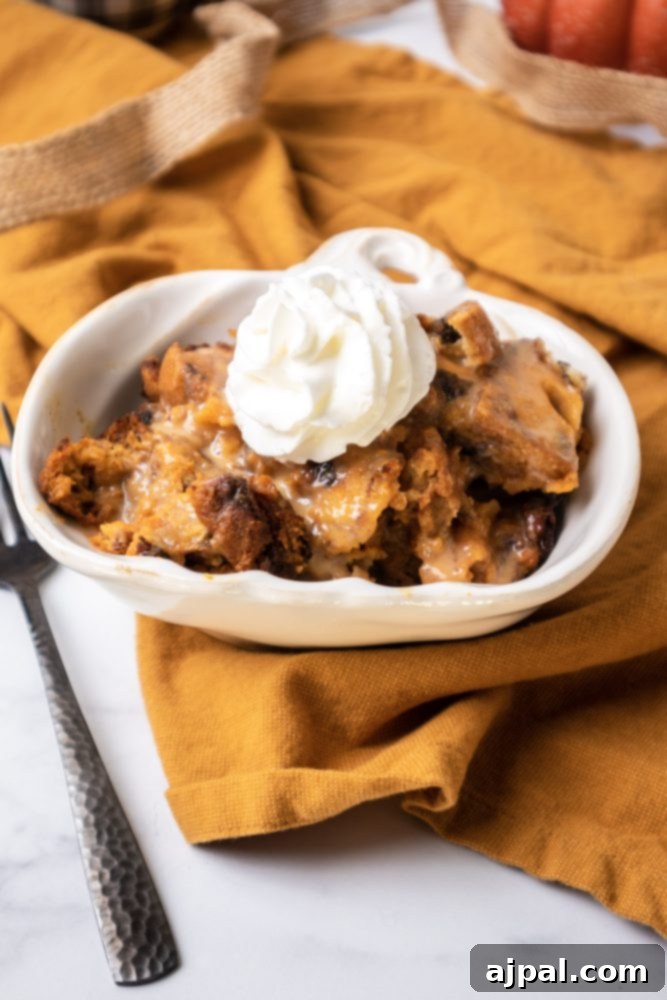 Slow Cooker Pumpkin Bread Pudding: A Cozy Autumn Dessert 4 A close-up shot of slow cooker pumpkin bread pudding, topped generously with whipped cream, on a white serving dish.