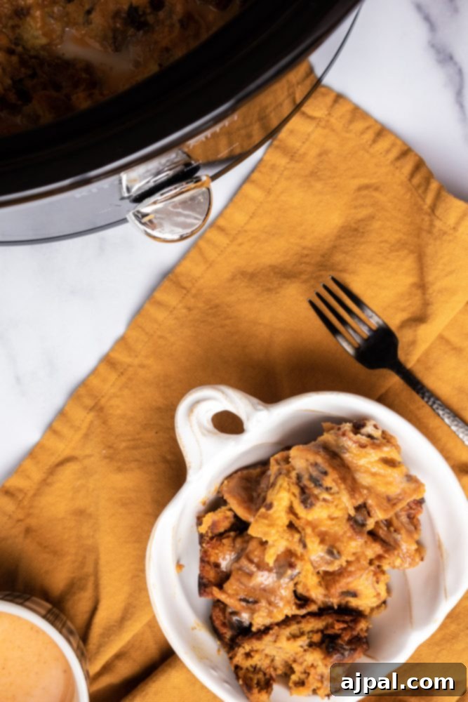 Slow Cooker Pumpkin Bread Pudding: A Cozy Autumn Dessert 8 A serving of slow cooker pumpkin bread pudding with whipped cream and a fork, next to the slow cooker itself.