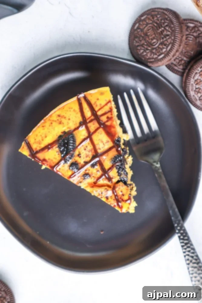 Instant Pot Pumpkin Oreo Dream Cheesecake 5 A delicious slice of Instant Pot Pumpkin Oreo Cheesecake garnished with crushed Oreos and chocolate drizzle.