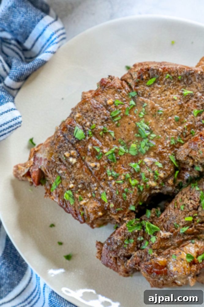 Fork-Tender Dr Pepper Instant Pot Pot Roast 3 A close-up shot of the tender Dr Pepper pot roast on a white plate, garnished with fresh herbs, showcasing its rich, inviting appearance.