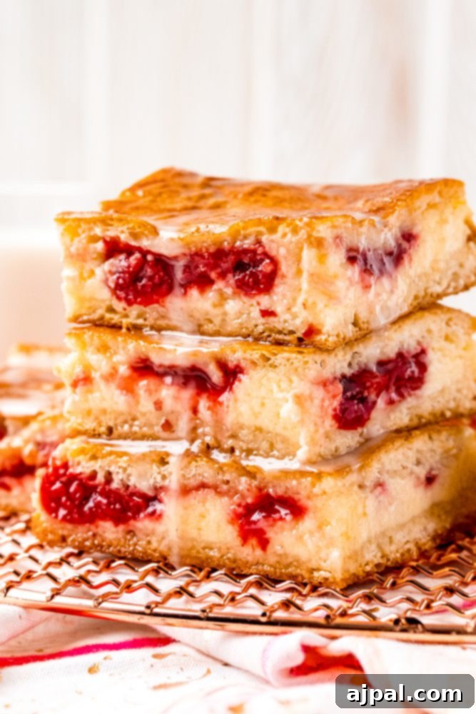 Baked cherry danish pastry bars with a vanilla glaze stacked on a wire rack