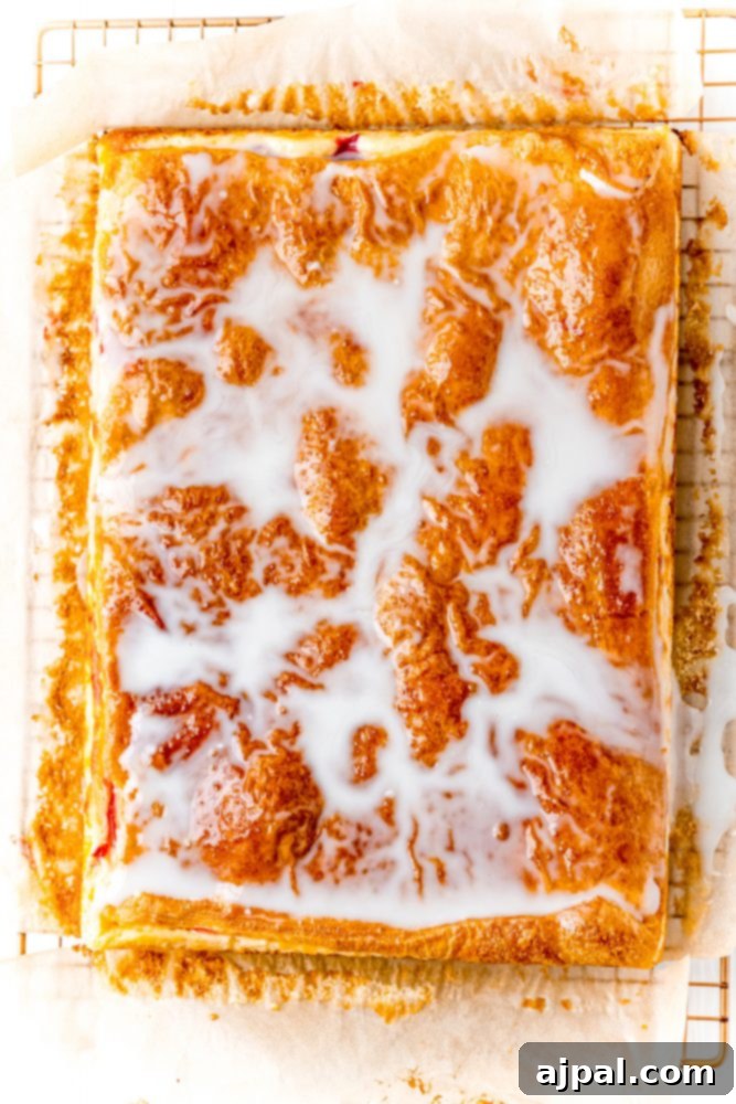 Glazed cherry cheesecake pastry on a cooling rack on a table