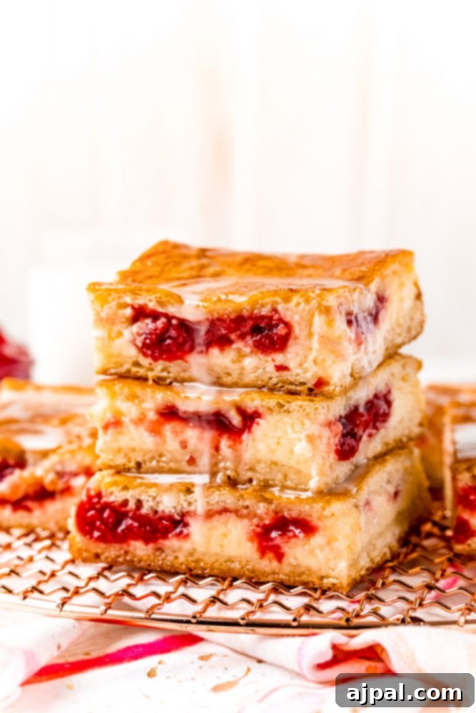 A stack of cherry cheesecake bars on a plate with a glass of milk.