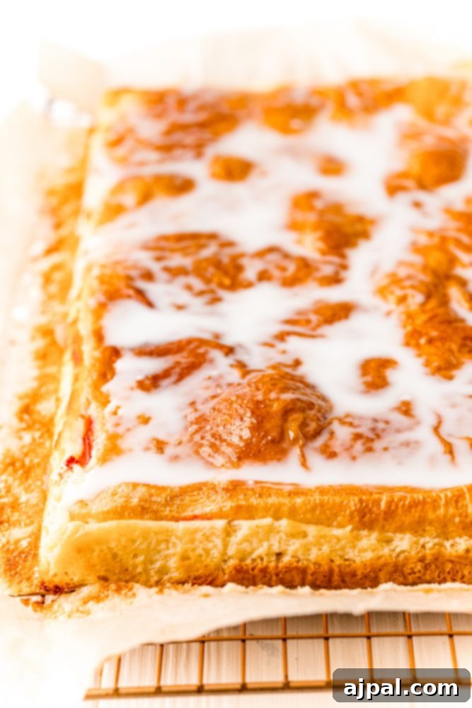 Baked cherry cheesecake pastry glazed with icing on a wire rack