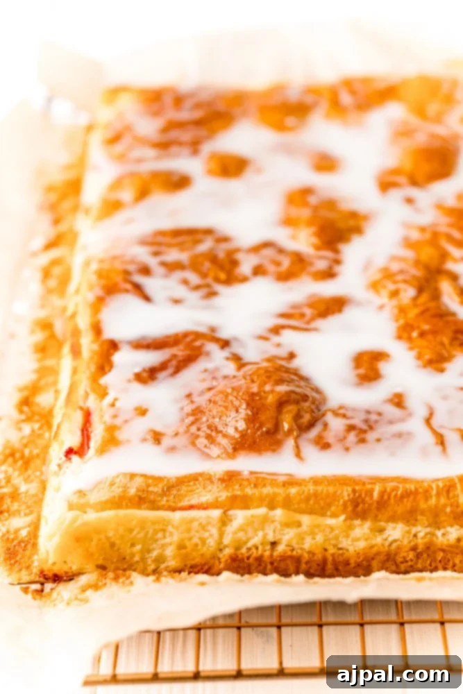 baked cherry cheesecake pastry glazed with icing on a wire rack