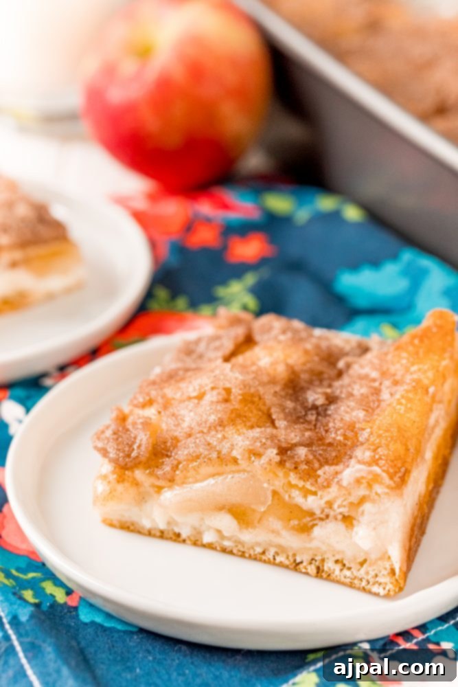 A close-up of a slice of baked apple sopapilla cheesecake, highlighting its golden crust and delicious layers.