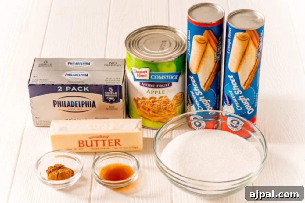 Ingredients for Easy Apple Sopapilla Cheesecake laid out: crescent dough, cream cheese, apple pie filling, butter, cinnamon, sugar.