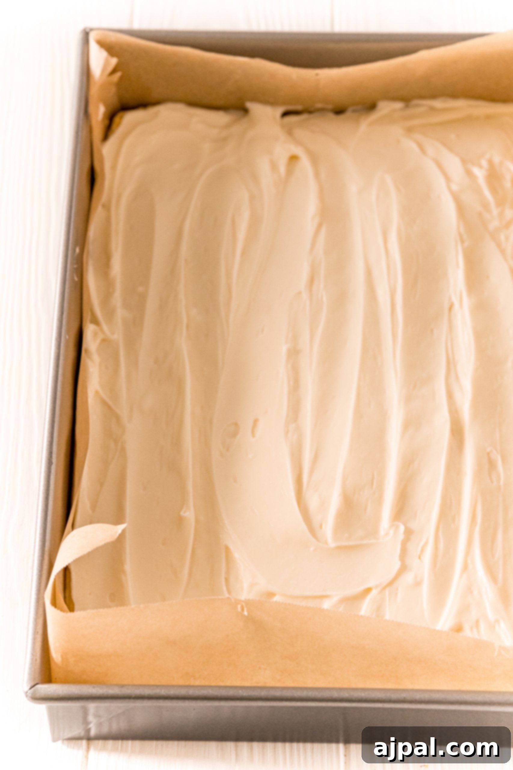 Cream cheese filling spread evenly over the bottom dough layer in a baking dish.