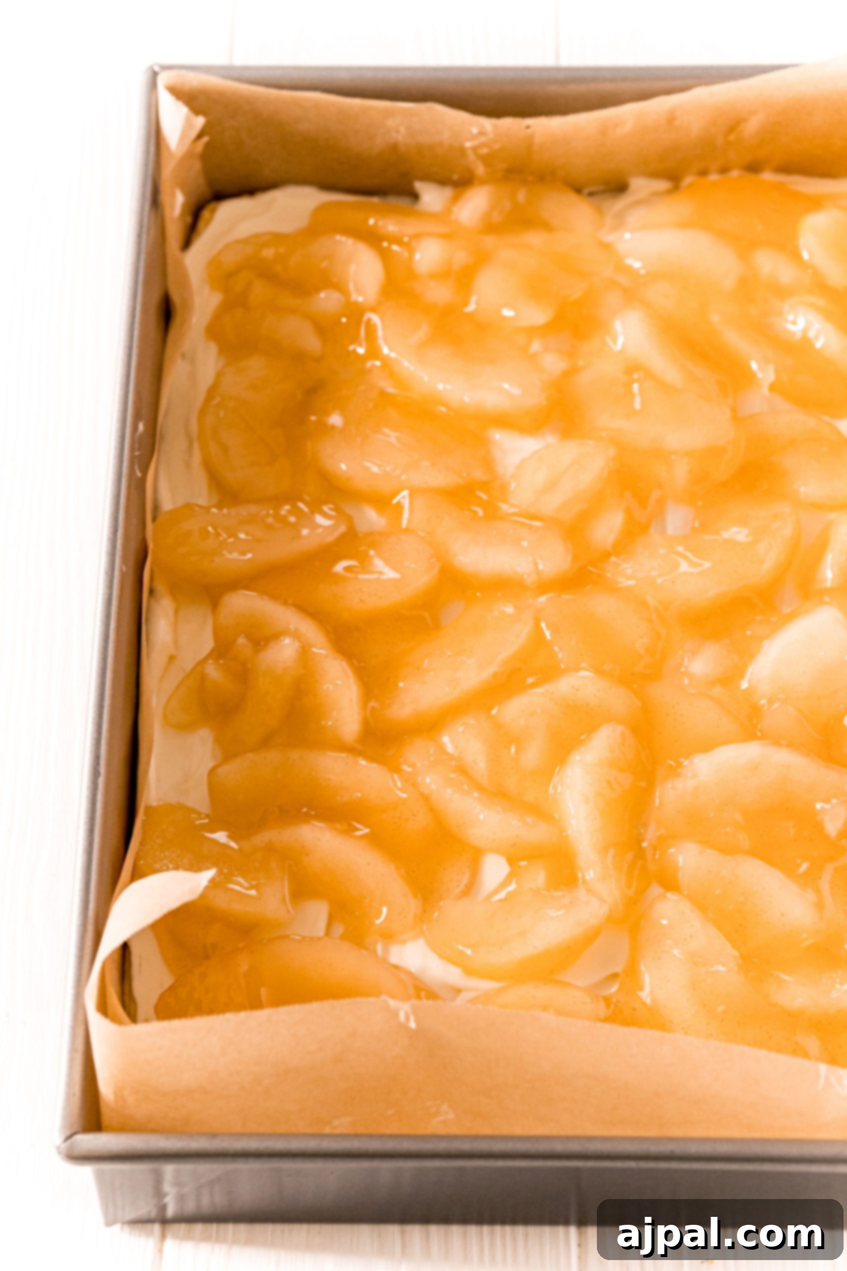Apple pie filling spooned over the cream cheese layer, ready for the top dough.